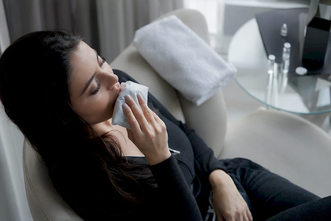 Woman applying cold compress to swollen lips