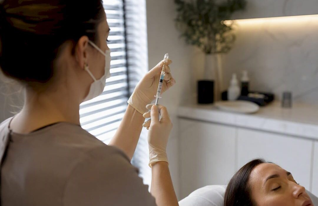 Clinician preparing Botox syringe near forehead
